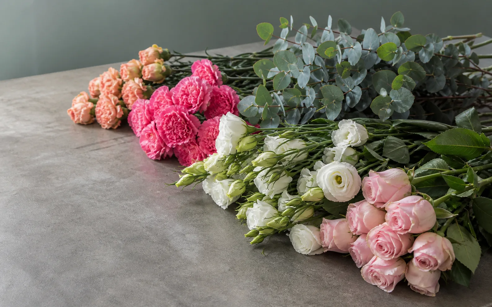 Bunches of carnations, eucalyptus, lisianthus and roses on a worktable — AI-generated illustration, not Hubfresh photography.