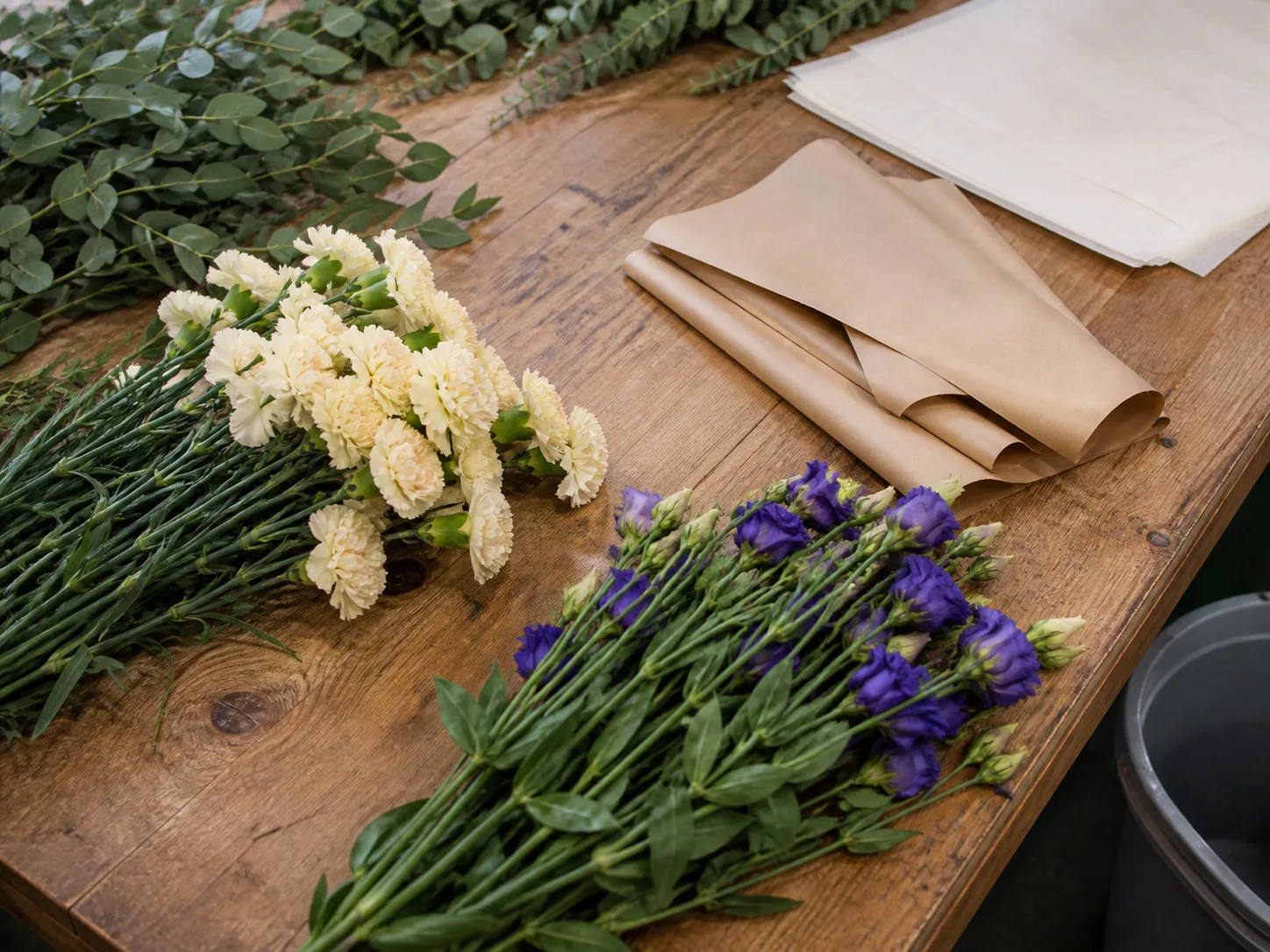 Cut flowers and paper sleeves on a packing worktable — AI-generated illustration, not Hubfresh photography.